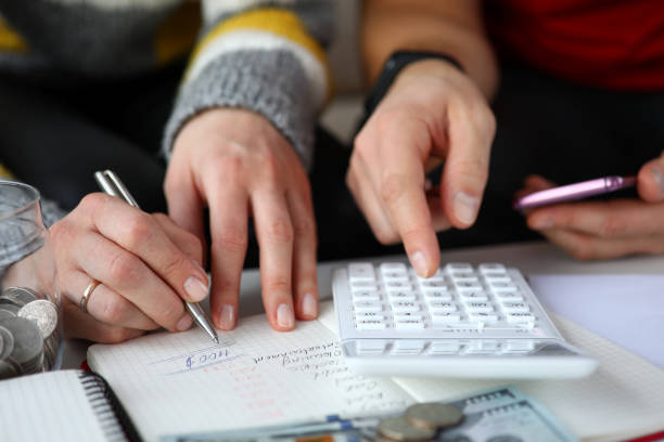 Casal listando e calculando os ganhos e os gastos mensais e construindo orçamento familiar