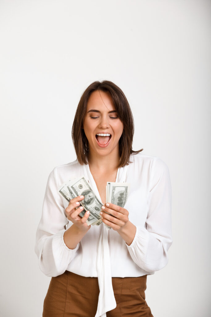 MULHER FELIZ SEGURANDO NOTAS DE DINHEIRO QUE CONSEGUIU GANHAR FAZENDO RENDA EXTRA PARA JUNTAR  DINHEIRO NO FIM DO MES