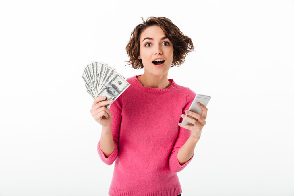 Mulher feliz e surpresa com a mão cheia de dinheiro, porque aprendeu a ganhar mais dinheiro com renda extra